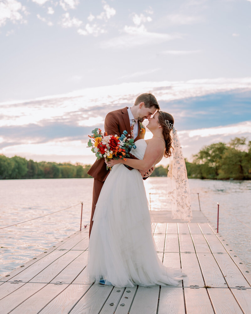 A couple stands forehead to forehead on a boat.