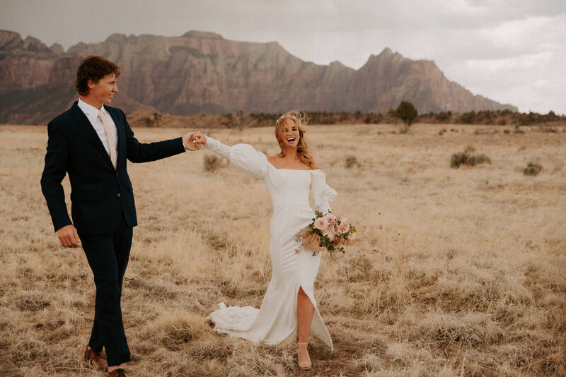 groom twirling his bride with an epic view behind them near Zion National Park on an overcast day