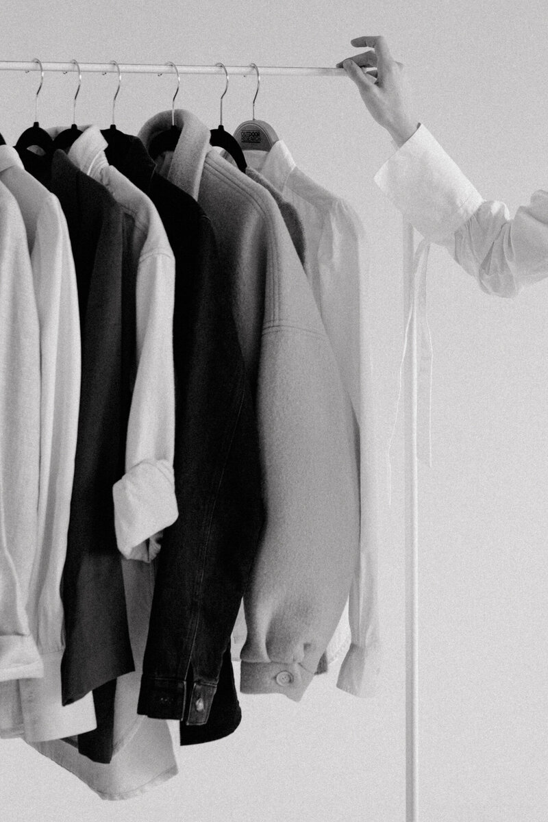 woman holding onto a clothing rack with clothings hanging