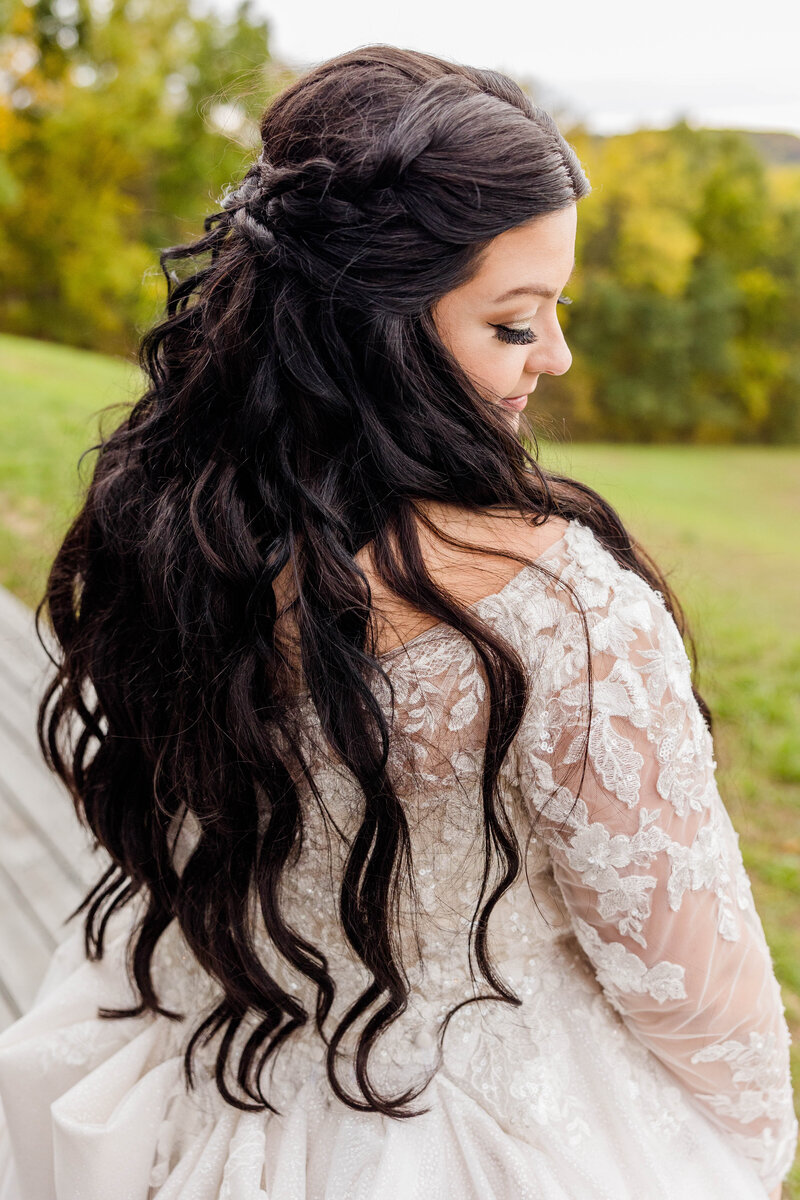 Bride with long dark hair showing off back of wedding dress.