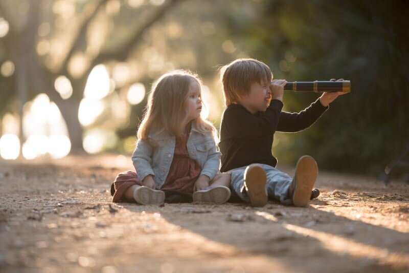 brother-and-sister-look-through-a-looking-glass-at-sunset-in-washington-oaks-park