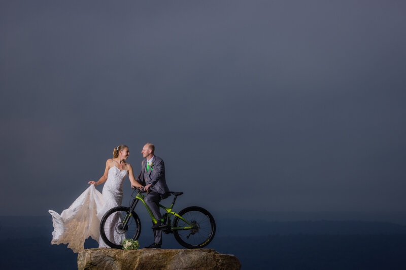 Couple at sunset with a mountain bike at the Blue Mountain lookout, blending adventure and romance in the Poconos.