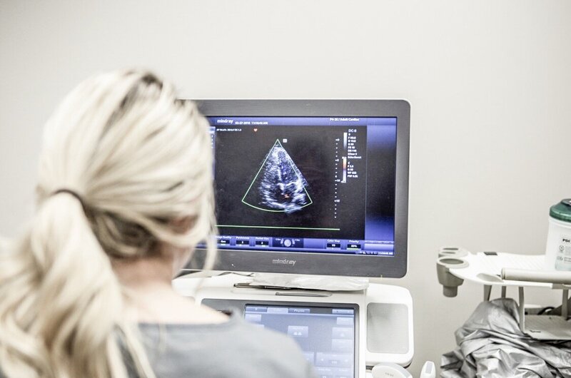 sonographer sitting at an ultrasound system, looking at images on the screen