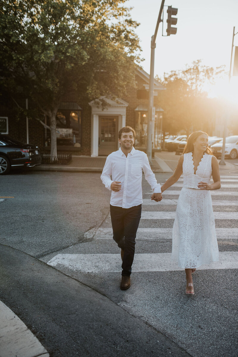 a couple holding hands while crossing the street at golden hour