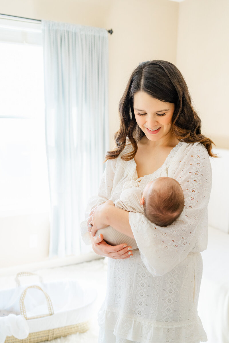 Austin, TX Family & Newborn Photography | A mother stands in a nursery and holds her newborn baby in her arms. 