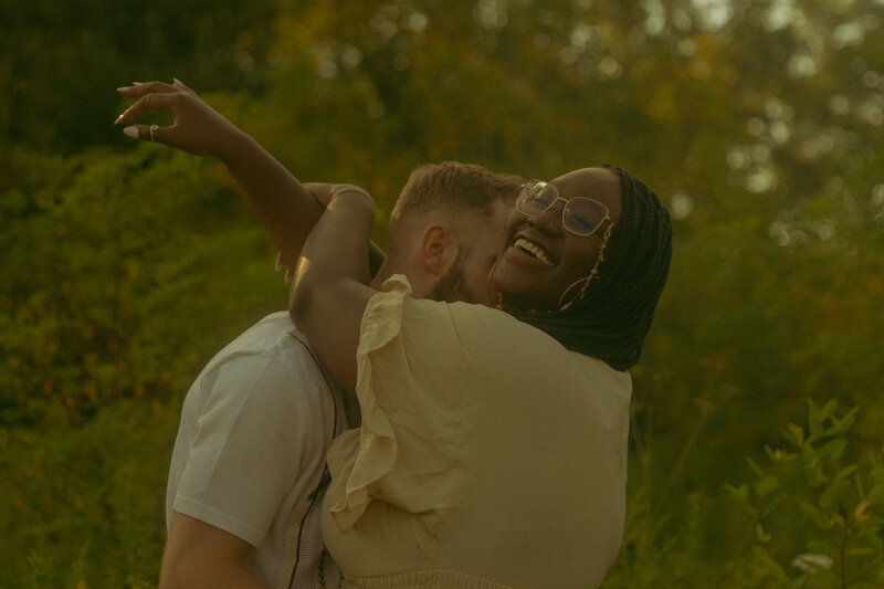 Newlyweds gaze into eachothers eyes on a brisk summer evening while the sun glares between their faces and her veil gets carried in the wind