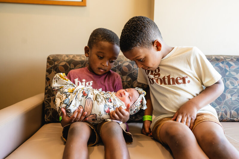 Older sibling holding newborn baby for the first time at home — heartwarming family Fresh 48 photography in Fort Worth by Poppy + Blue Photography