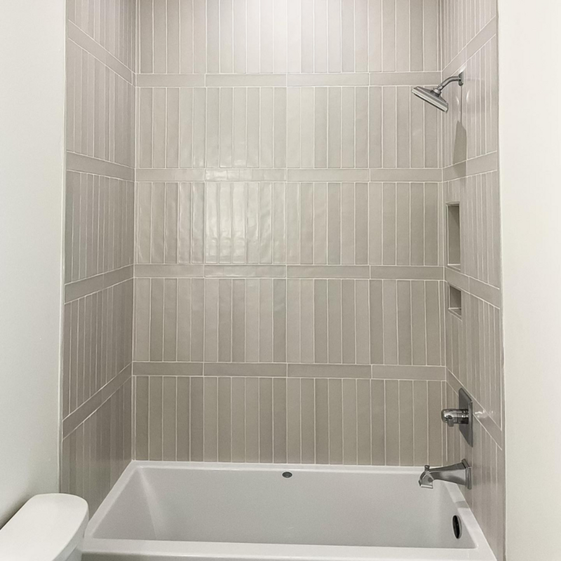 Custom shower with gray matchstick tiles.