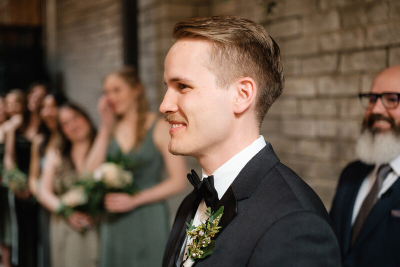 Groom smiles when he sees the bride walking up the Aisle