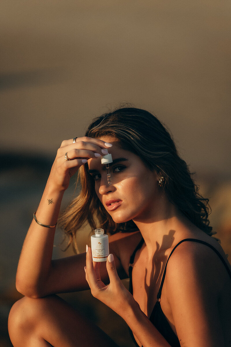 Luxury skincare brand photography featuring a woman applying a facial serum with golden sunlight highlighting her glowing skin. Cinematic and storytelling brand photography for beauty and wellness brands, captured on the Sunshine Coast.
