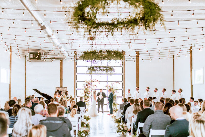 Bright inside of barn, tons of natural light. Bride and groom at the altar.