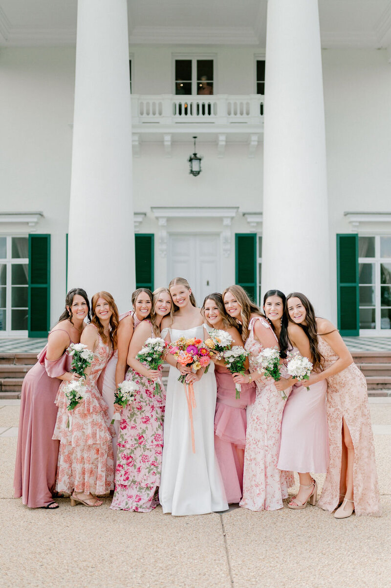 a bride posing for a photo with her bridesmaids who are dressed in pink