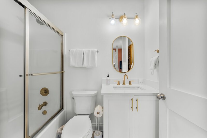 Clean guest bathroom with gold fixtures and modern lighting, located in Groovy Shack in Panama City Beach near 30A and Carillon Beach.