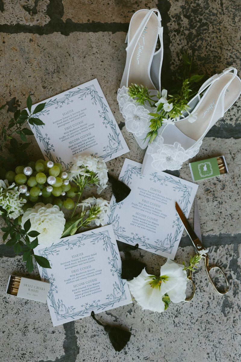 Flatlay of a custom invitation suite in shades of green, representing calligraphy for wedding invitation by Life in Letters.