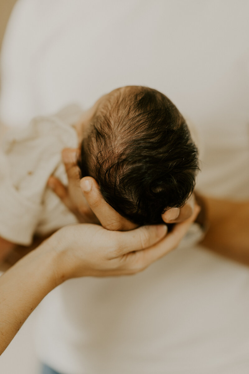Pieds de bébé tenus dans les mains des parents, immortalisés par Laura, photographe en Vendée.