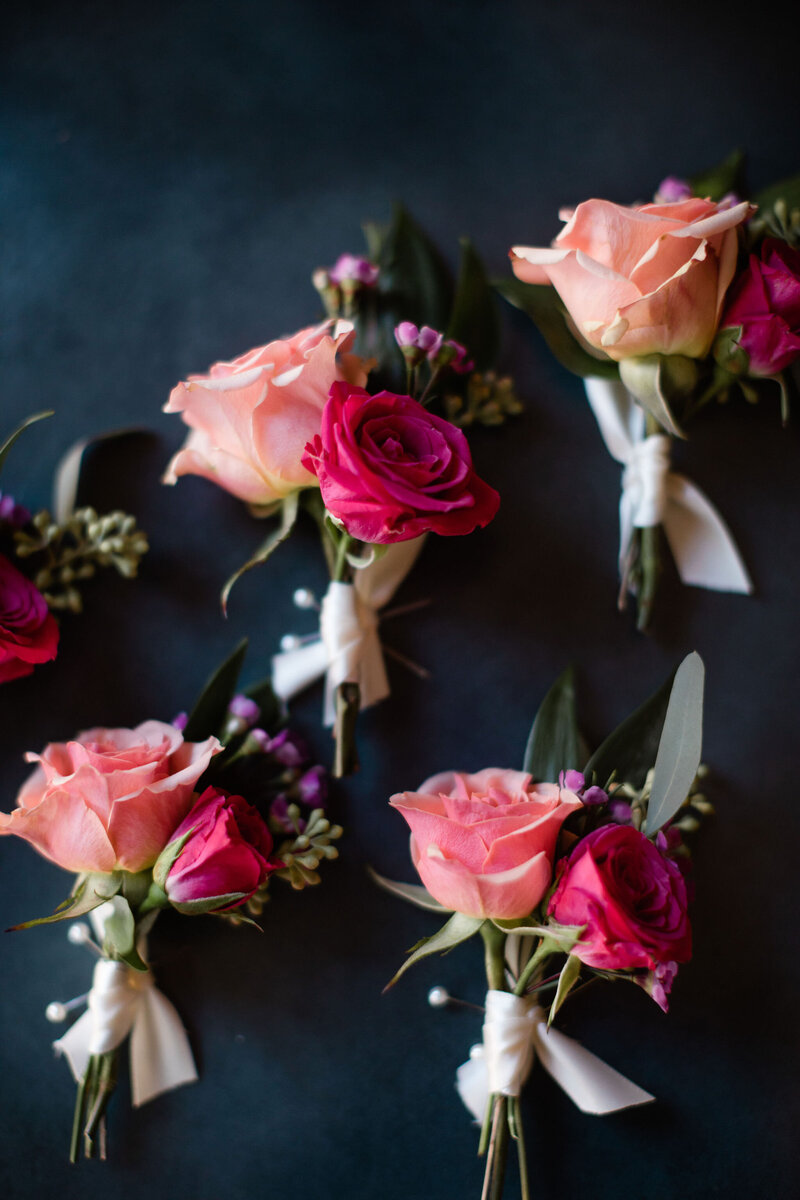 Pink flower boutonnieres laying on a black background