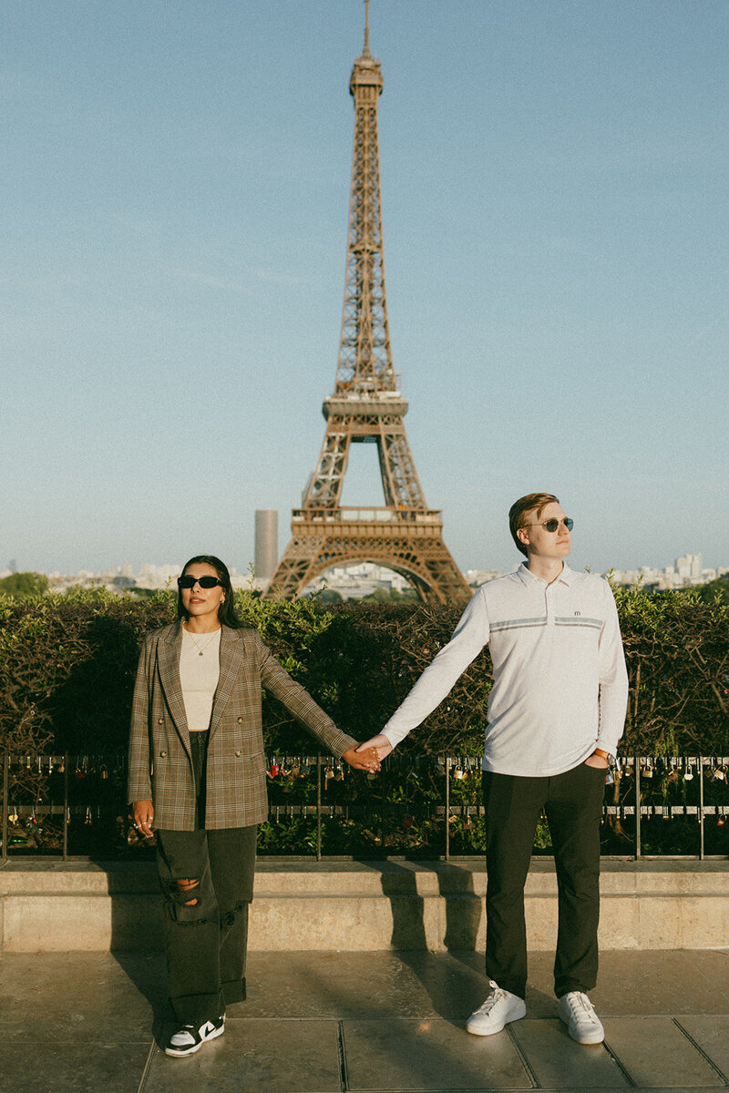 A couple holding hands in front of the Eiffel Tower in Paris, France.