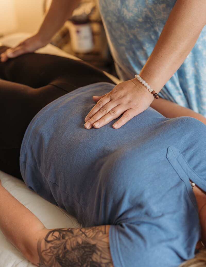 Wellness practitioner performing energy balancing session with gentle hand placement on a patient’s back.