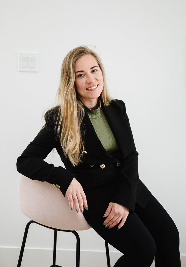 Realtor Tamara sitting on a pink h chair in a white, clean house