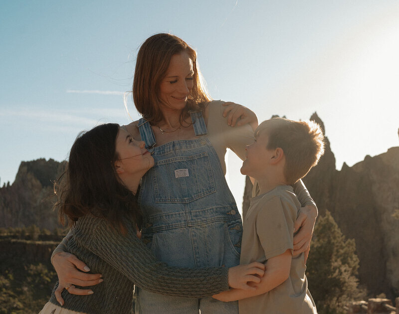 mother and children embracing and smiling in front of Smith Rock in Bend, Oregon