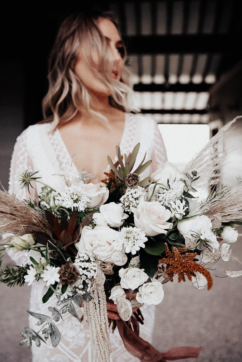 Elegant bohemian bridal portrait at Shem Creek holding luxurious wedding bouquet