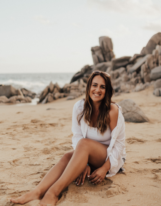 Girl with brown hair sat on a beach