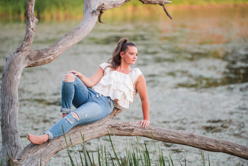 a high school senior girl laying on a tree branch