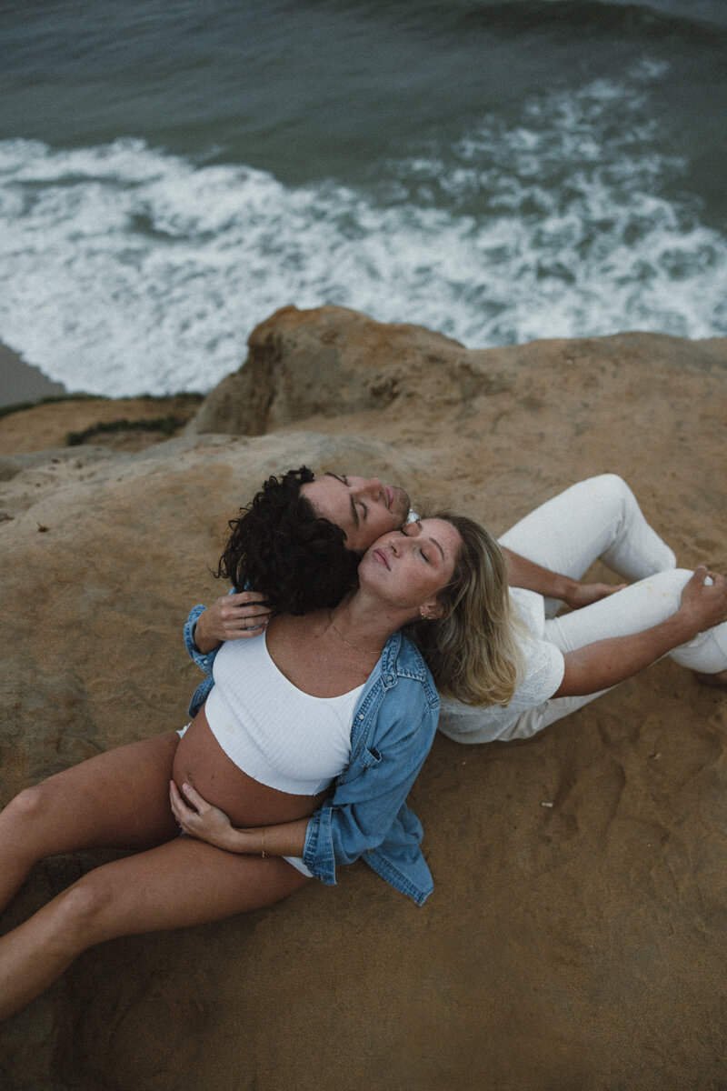pregnant-couple-sitting-on-a-cliff-in-san-diego