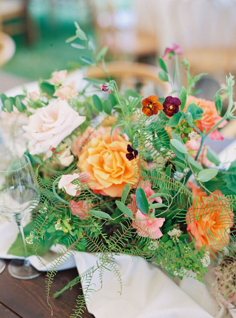 Close-up of wedding centerpiece with peonies, ranunculus, carnations, pansies, and garden roses, in coral and peach tones by Summer Robbins Flowers in Bend, Oregon