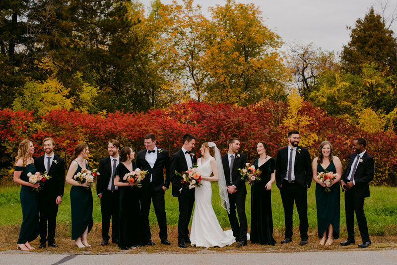 wedding party in black and white  standing in front of red sumac trees
