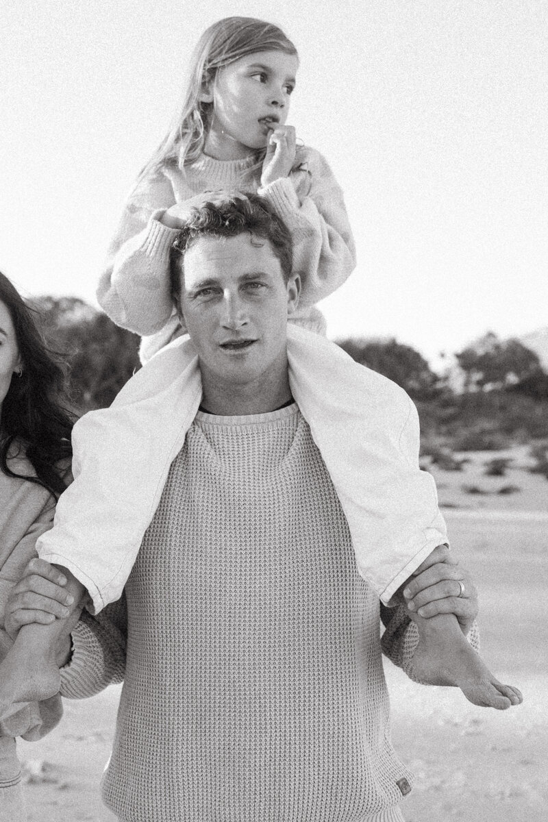 A daughter ists on her dads shoulders at Cabarita Beach