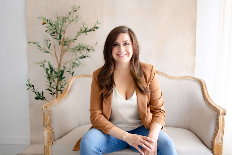 Ashley Mulligan, Wedding Planner, smiling at the camera wearing a tan blazer in a brightly lit room