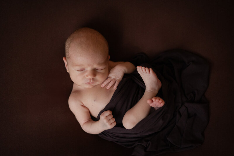 Puur en minimalistisch: een newborn fotoshoot aan huis waarbij de baby centraal staat op een witte achtergrond.