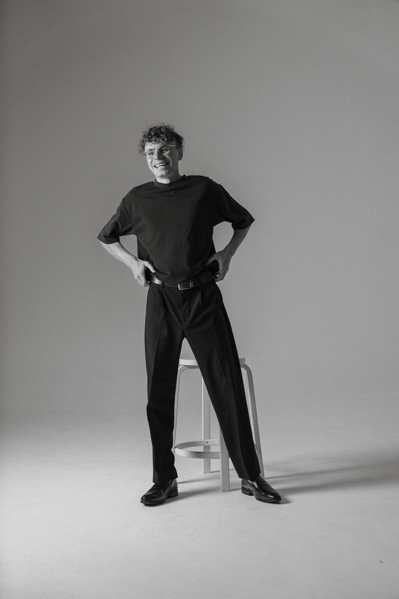 man in studio pulling up pants and smiling