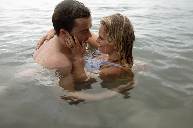 A couple is embracing in the water , they are looking at each other | Engagement Photographer | Rebecca Rottcher 