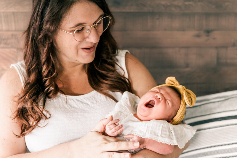 Mom holding baby with yellow bow on head