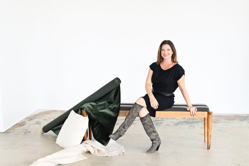 Interior designer in Lake Norman, NC, sitting on a bench with fabric samples, showcasing full-service interior design and planning expertise.
