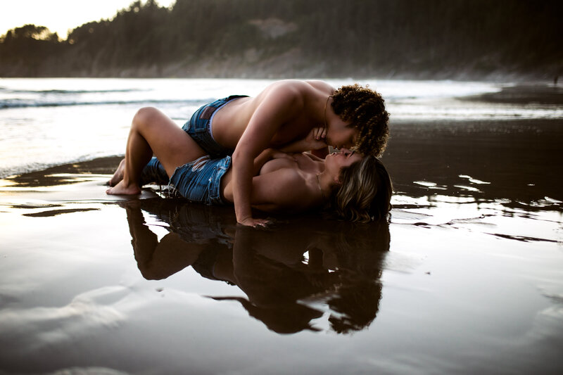 Couple lying together near a reflective lake, showcasing tender love, captured by an Oregon Coast Elopement and Wedding Photographer.