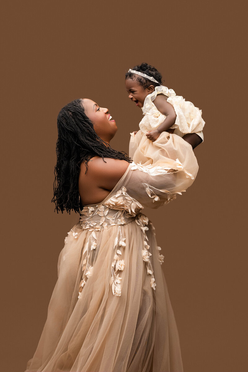 Mother lovingly breastfeeding her baby while wearing a green sequined gown against a deep green backdrop.