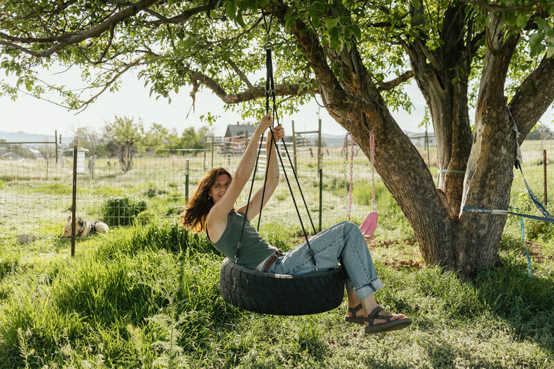 Motion picture of a woman swinging on a tire swing smiling and laughing