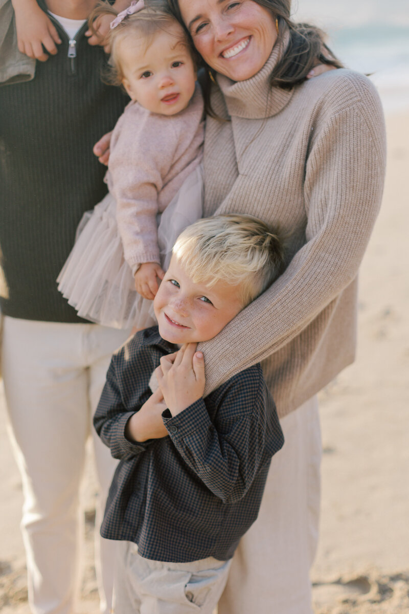 Kid smiles for camera during family photos at Westward beach by Malibu photographer