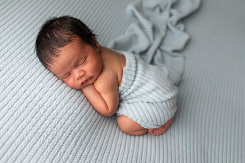 newborn boy wrapped in blue fabric