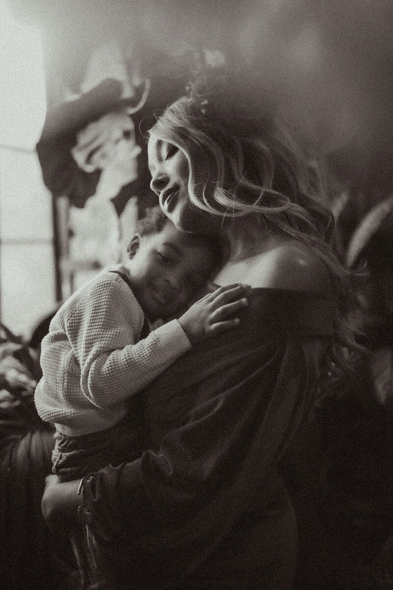 A mother holding her baby boy close and closing her eyes to soak up the moment. 