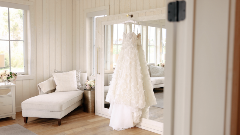 Intricate dress hanging in front of mirror, light and airy photo taken at River Bottoms Ranch by Cali Warner Media