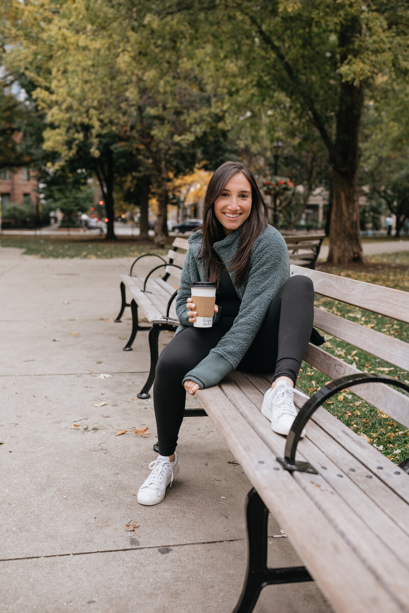 Jordan Hana relaxing on a park bench with coffee