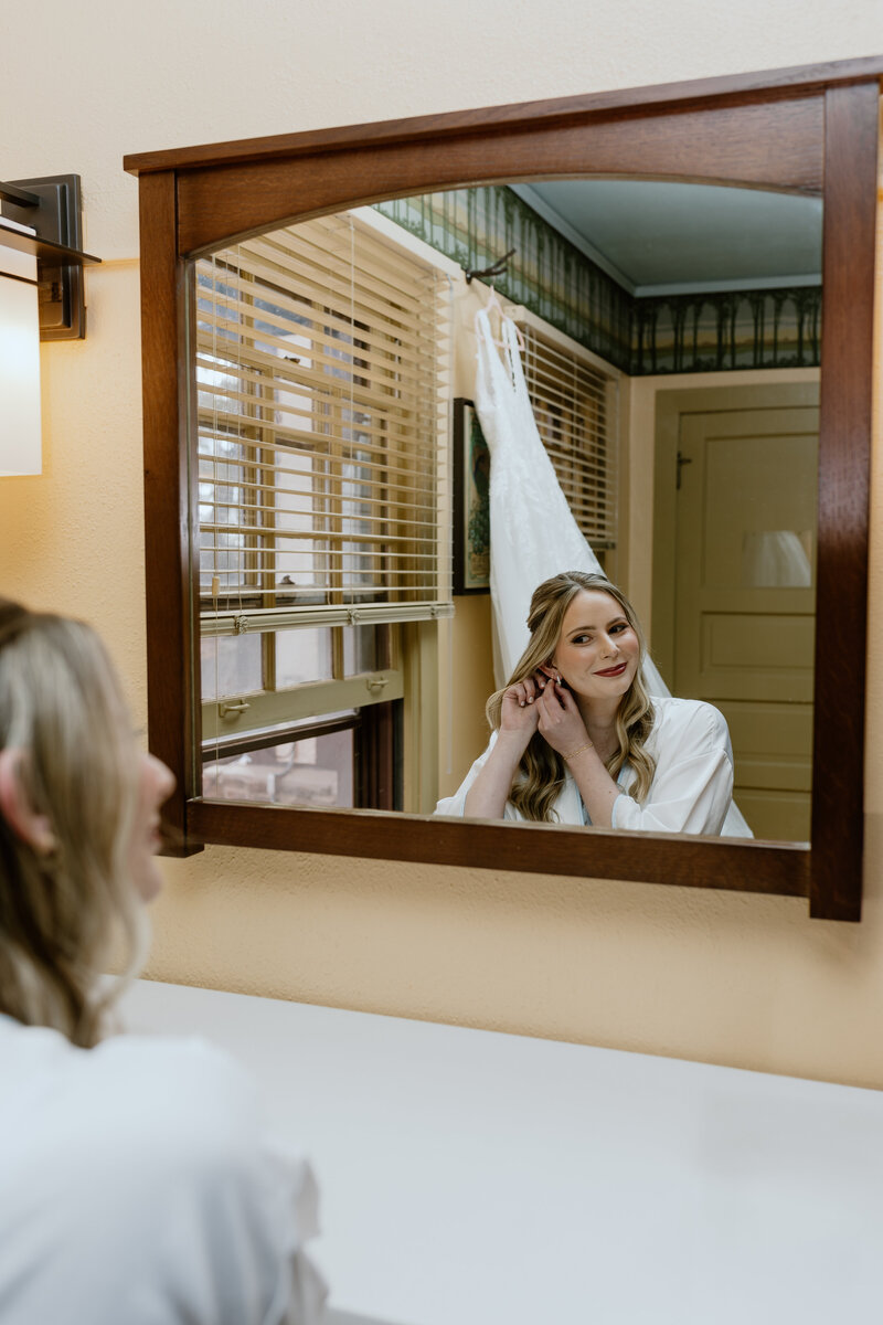 Timeless bridal moment as she looks at herself in the mirror at a rustic Colorado wedding venue