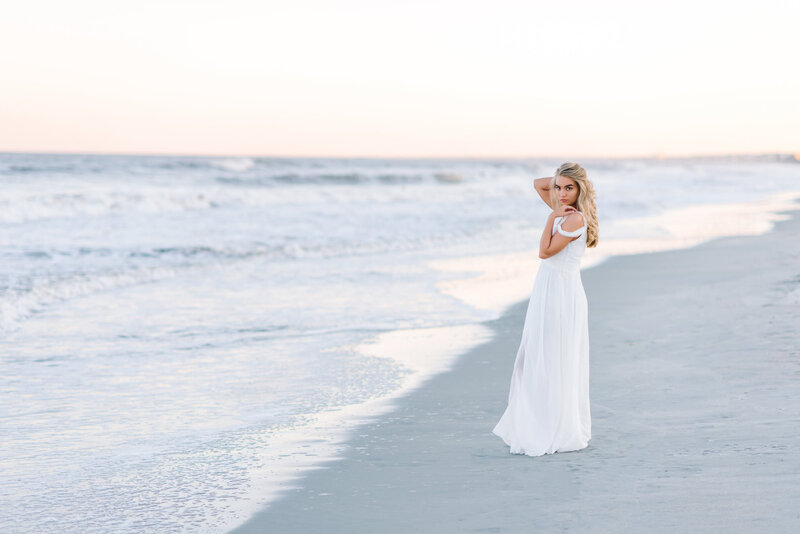 High school senior girl posing by the ocean during sunset in Myrtle Beach