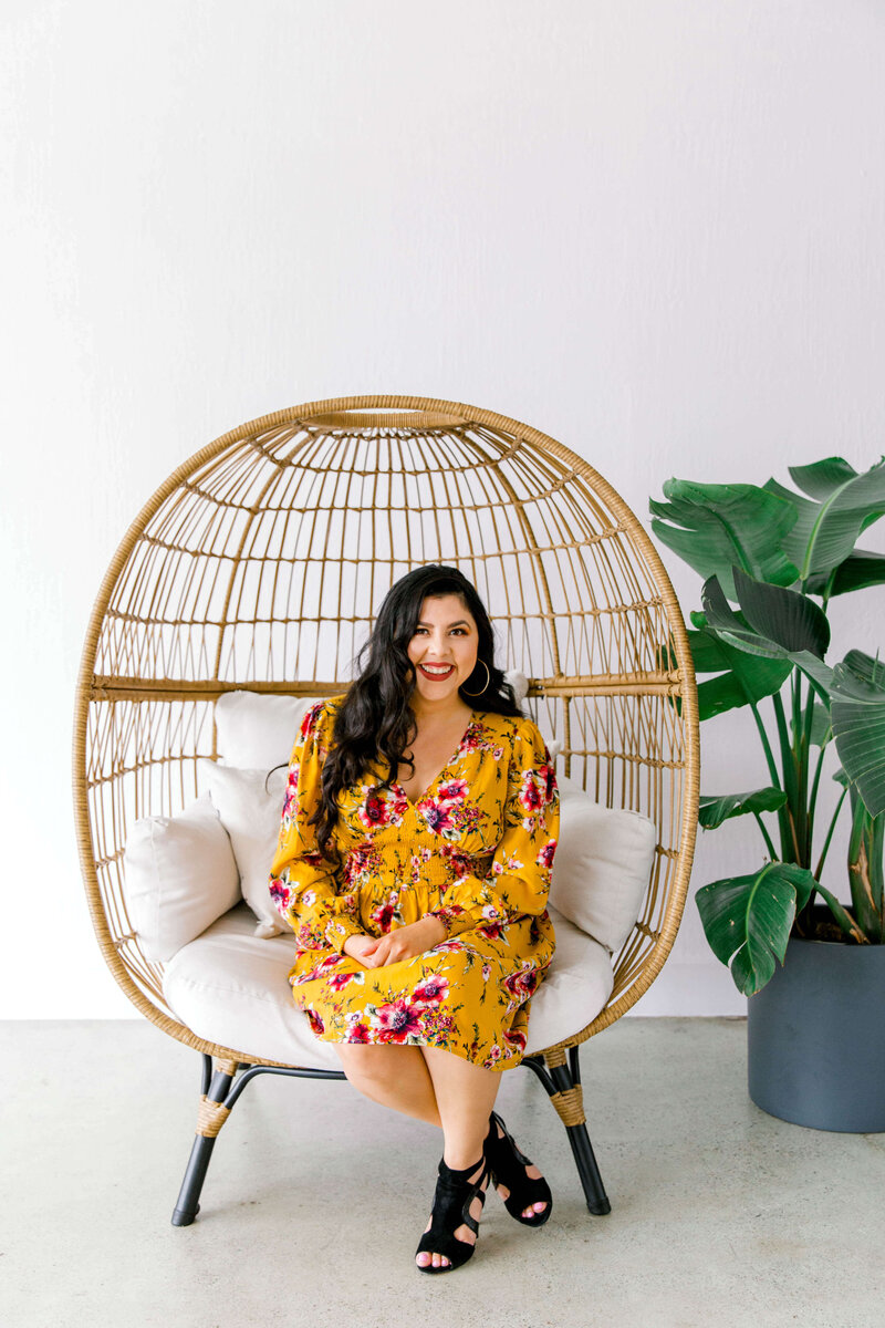 Celeste Gonzalez smiling while sitting on a rattan chair