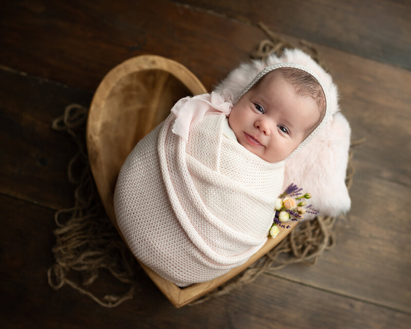 Pure joy captured in a heart bowl—this baby girl’s smile is the softest welcome to the world.