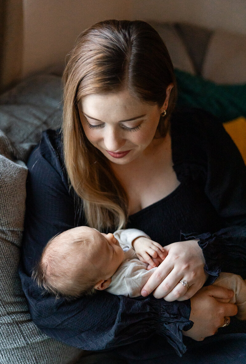 A mother gazing down at her newborn while sitting on her couch in the living room in Farmington, Missouri. 
